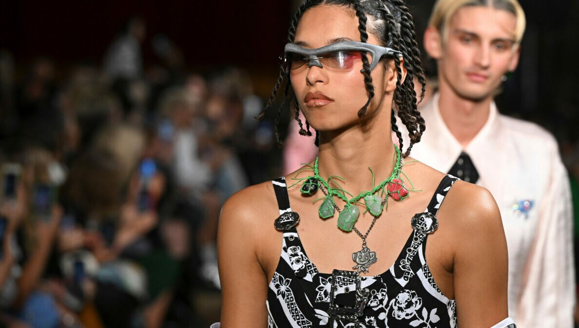 Nahaufnahme eines Models in extravaganter Kleidung und futuristischer Sonnenbrille bei einer Modenschau