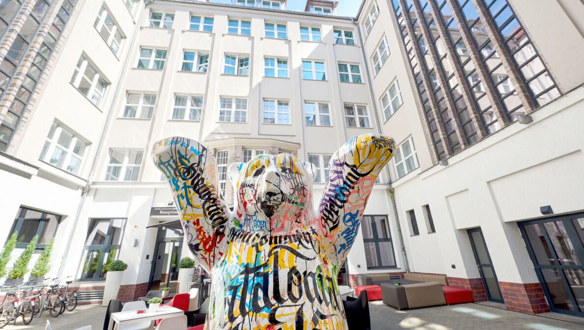 Die Statue eines bunten Berliner Bären steht im Innenhof eines mehrstöckigen weißen Hotels