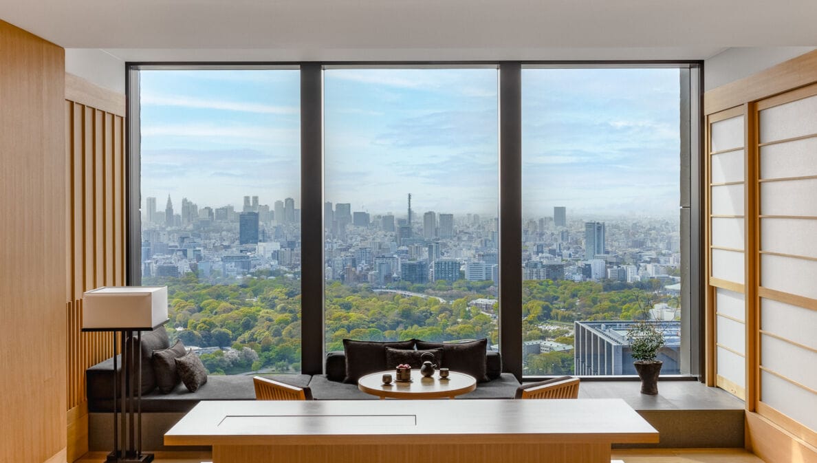Hotelsuite im japanischen Stil mit Blick durch ein bodentiefes Panoramafenster auf die Skyline von Tokio