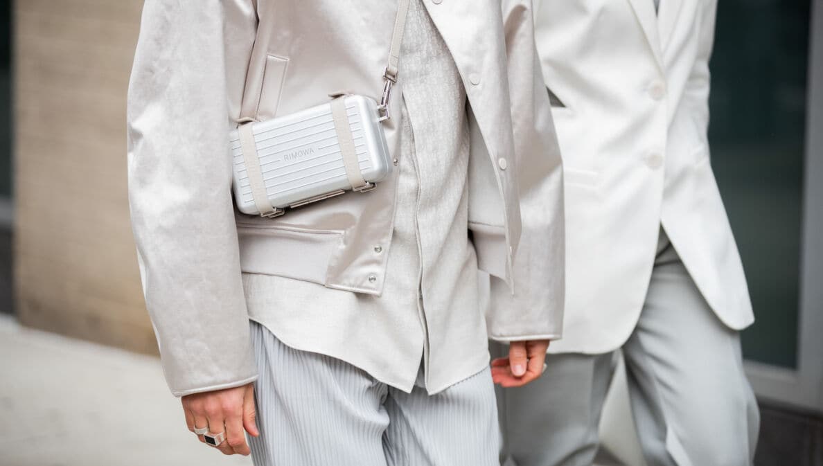 Models ins heller Businesskleidung tragen eine von Dior und Rimowa entwickelte Tasche