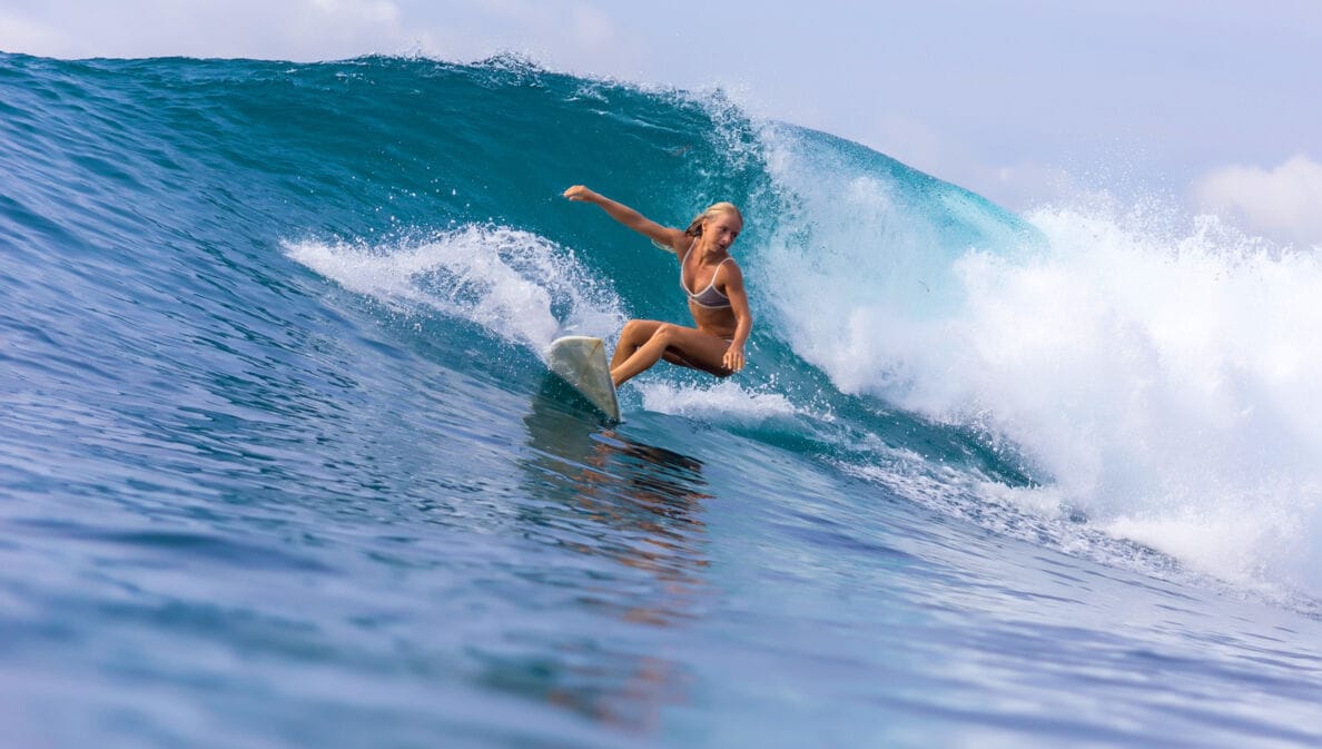 Eine junge Surferin im Bikini reitet auf einer großen Welle