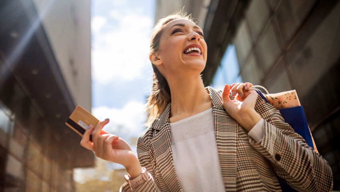 Porträt einer jungen Frau mit Kreditkarte und Einkaufstauschen in den Händen beim Einkaufen in der Stadt