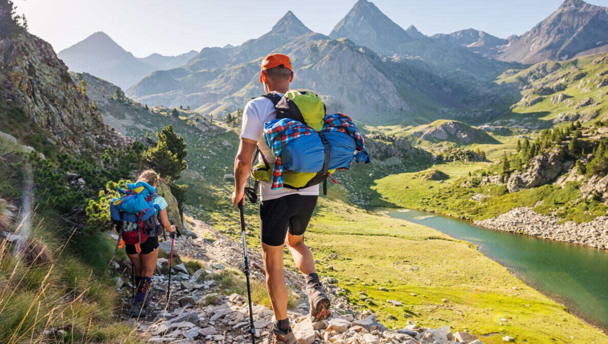 Rückansicht von zwei Wandernden mit Rucksäcken vor Bergpanorama in den Pyrenäen