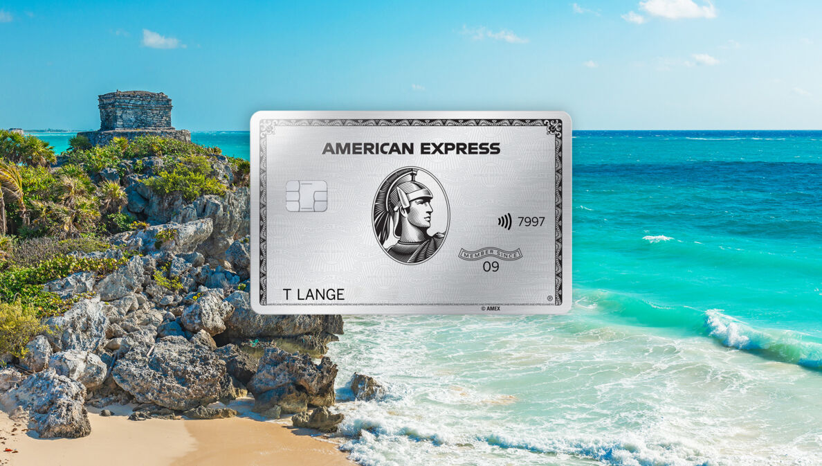 Fotomontage einer silbernen Kreditkarte von American Express vor Strandpanorama mit türkisblauem Wasser und Maya-Ruine auf einem Felsen.
