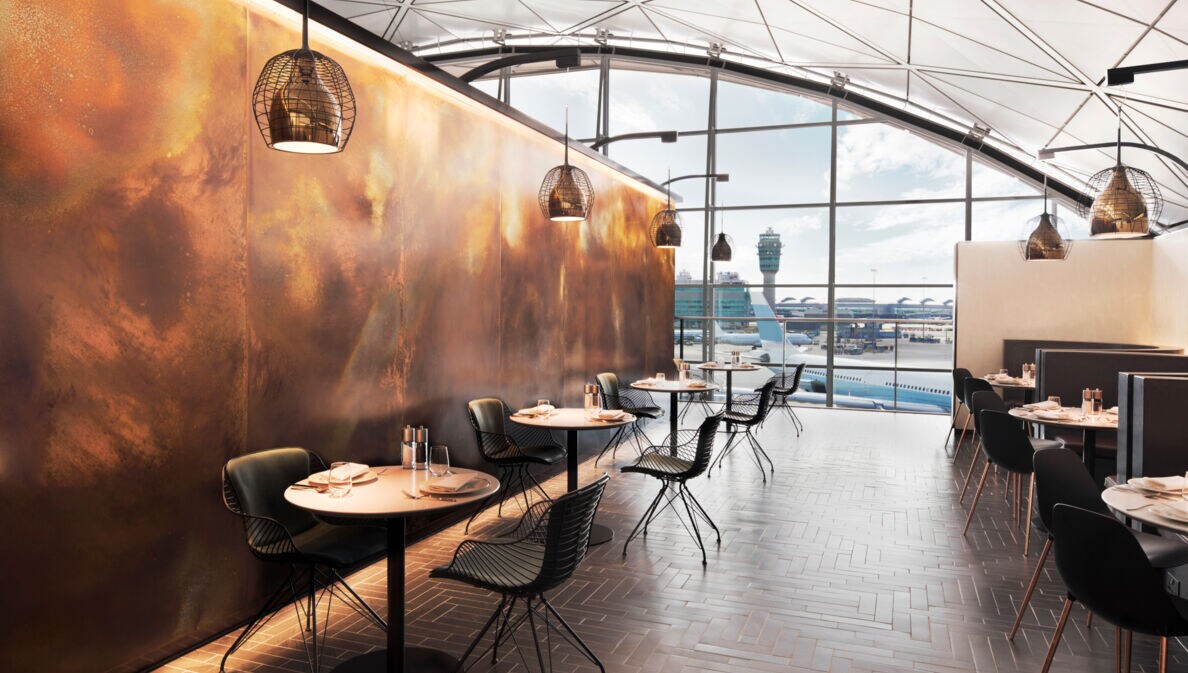 Modernes, edles Restaurant mit eingedeckten Tischen in einem Flughafen mit Panoramablick aufs Rollfeld