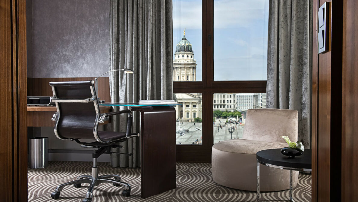 Luxuriöses Hotelzimmer mit Schreibtisch an einem bodentiefen Fenster mit Blick auf den Dom am Gendarmenmarkt in Berlin.