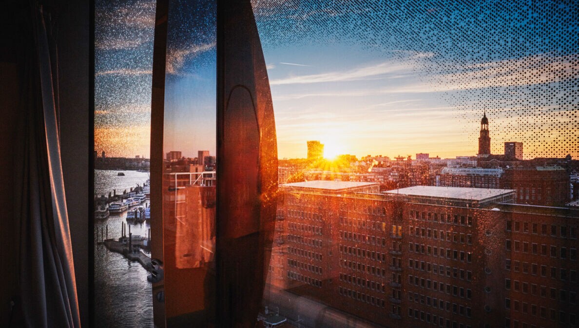 Stadtpanorama von Hamburg am Hafen aus einem geschwungenen Fenster bei Sonnenuntergang.