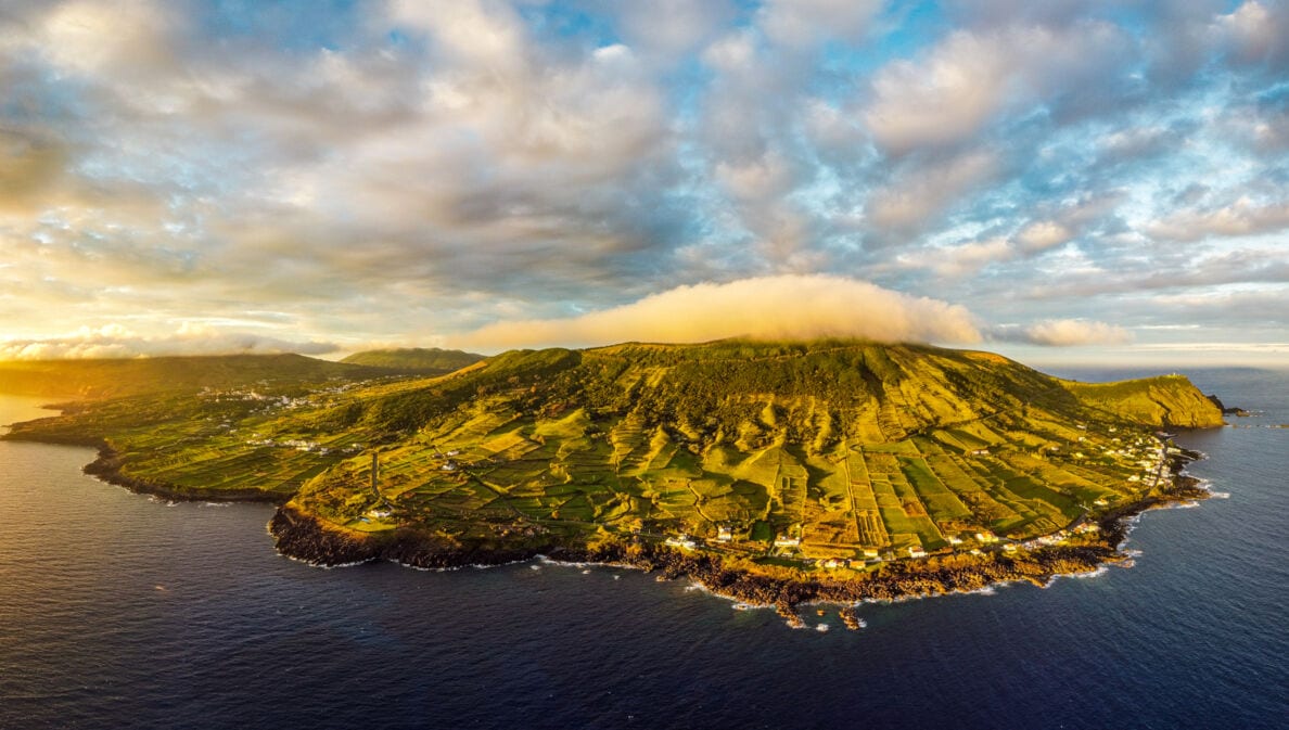 Luftaufnahme der Vulkaninsel Graciosa mit sanften, grünen Hügellandschaften bei Sonnenuntergang.