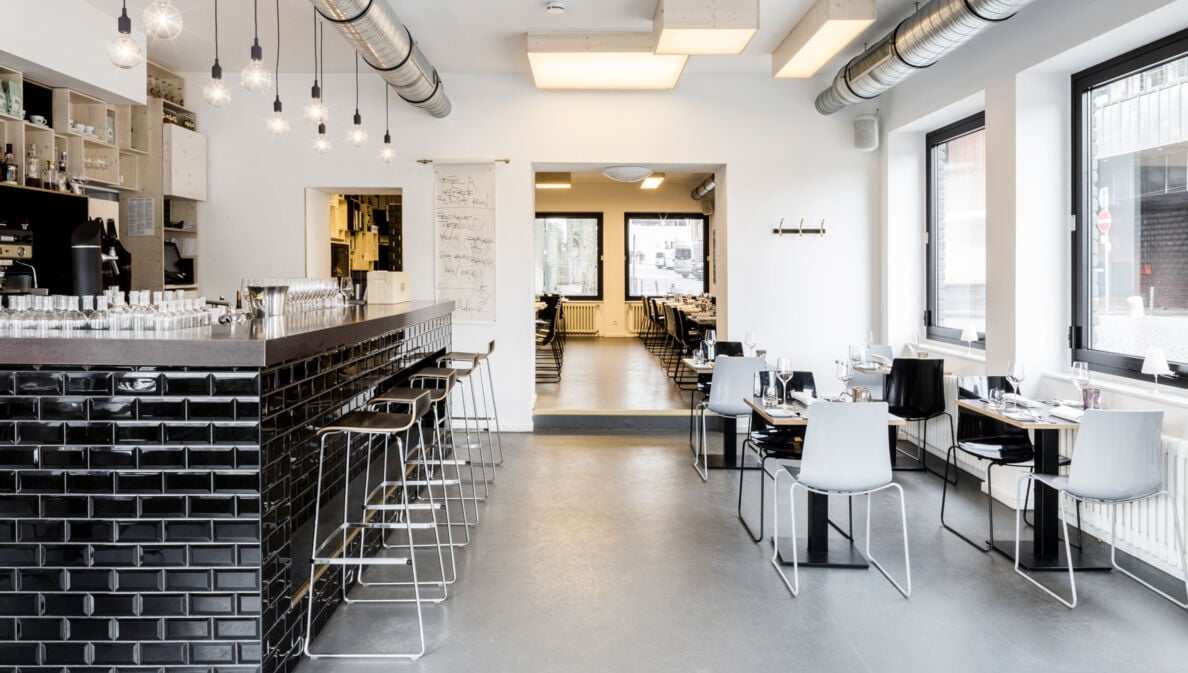 Speiseraum mit Tresen eines modernen Restaurants im industriellen Design und schwarz-weißer Farbgestaltung.