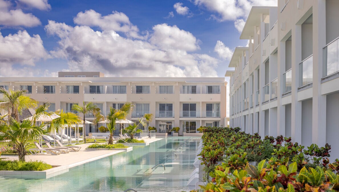 Moderne, dreistöckige Hotelanlage mit begrünter Poollandschaft.