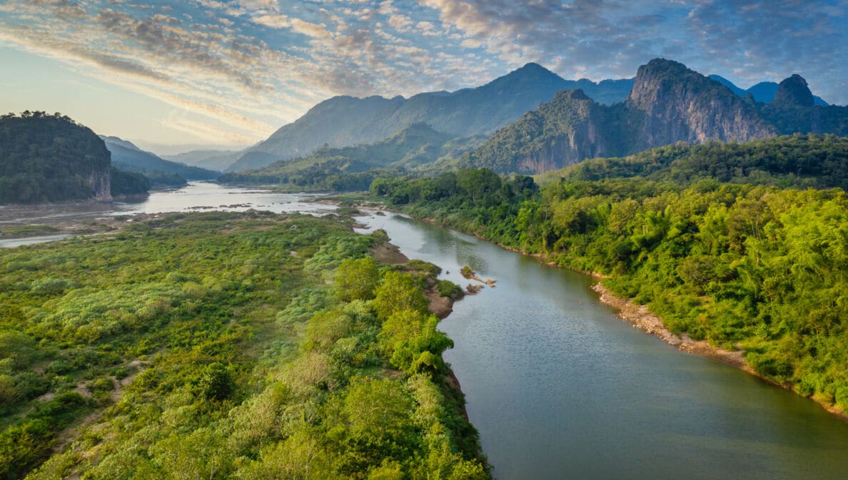 Flusslandschaft des Mekong in Laos mit Bergen im Hintergrund.
