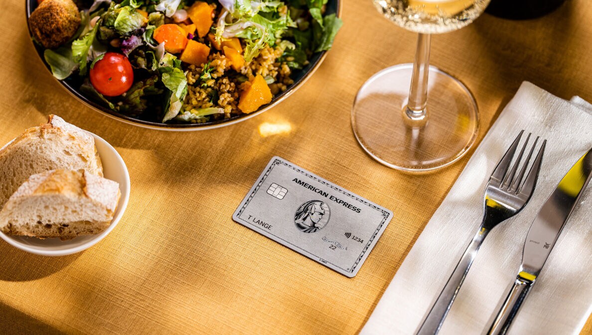 Eine Amex Platinum Card liegt auf einem gedeckten Tisch in einem gehobenen Restaurant