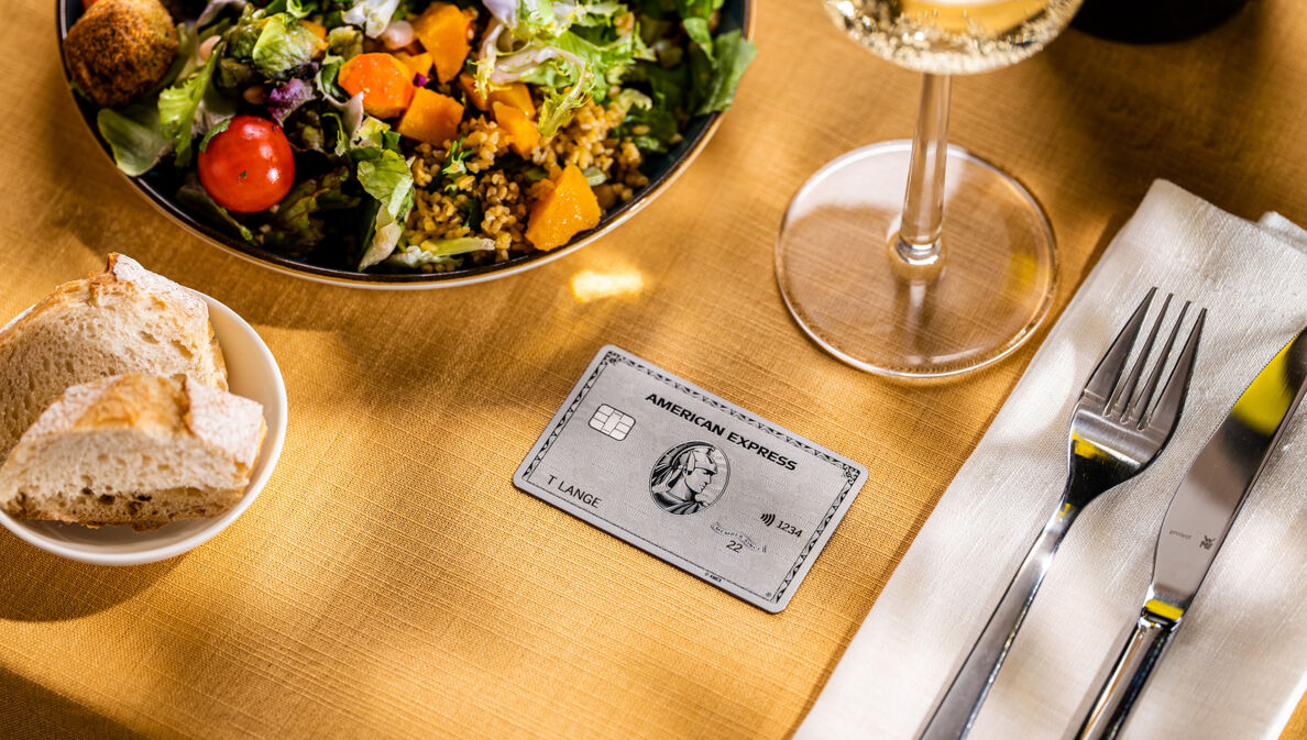 Eine Amex Platinum Card liegt auf einem gedeckten Tisch in einem gehobenen Restaurant