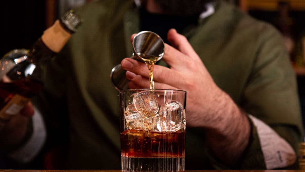 Ein Barkeeper gießt ein Glas Whisky ein.