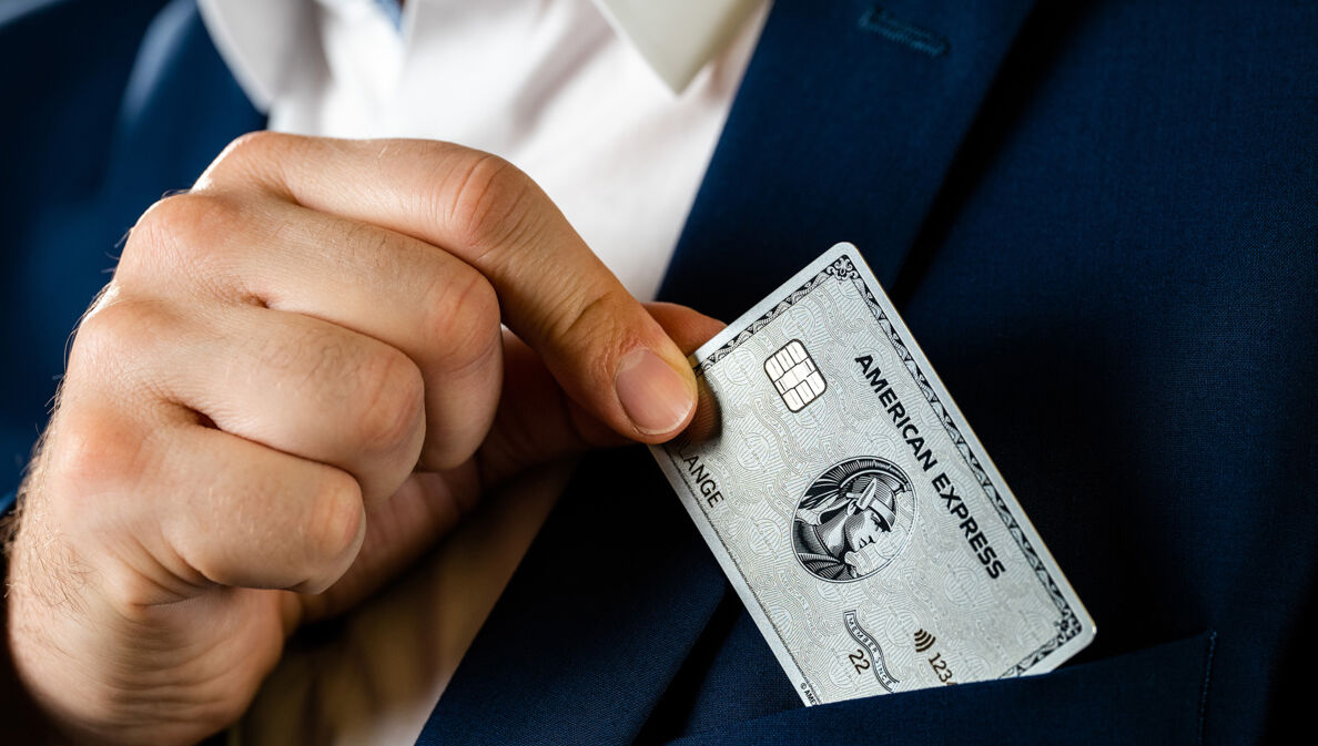 Eine Person steckt eine Kreditkarte in die Brusttasche eines Sakkos