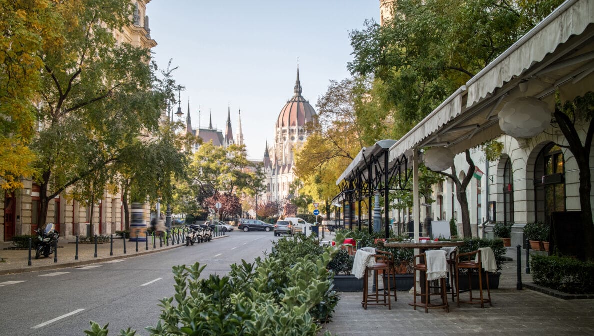 Straßenaufnahme in Budapest mit der Kuppel des Parlamentsgebäudes im Hintergrund. 