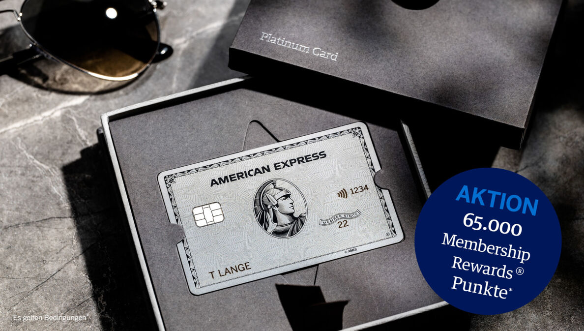 American Express Platinum Card aus Metall in einer geöffneten Präsentationsbox aus grauer Feinkartonage auf einem Marmortisch.