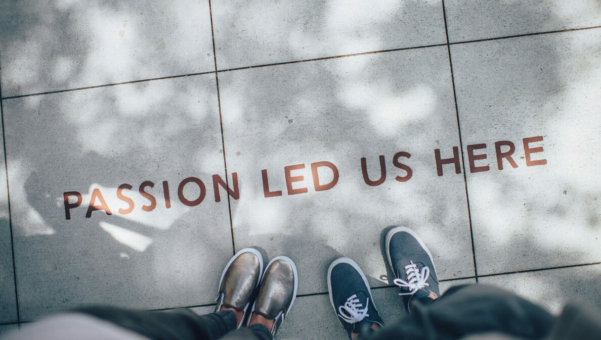 Zwei Personen lesen auf einem Gehweg den Schriftzug "Passion led us here"