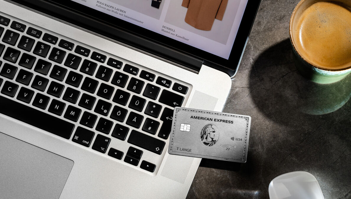 Eine silberne American Express Kreditkarte liegt auf einem Laptop beim Online-Shopping.