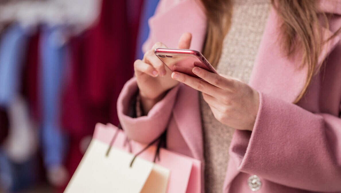 Eine Frau tippt beim Shopping auf ihrem Smartphone.