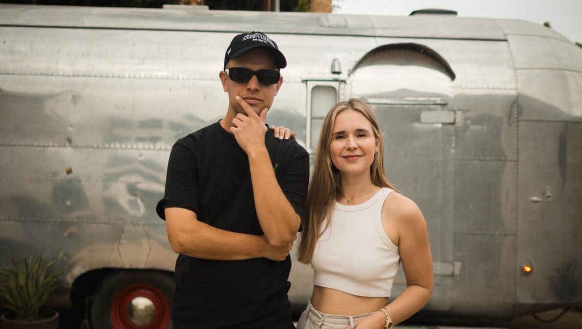 Sarah Emmerich und Benjamin Diedering stehen vor einem Wohnwagen in den USA.