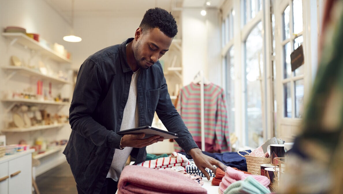 Ein Geschäftsinhaber prüft die Ware und benutzt dazu ein Tablet.