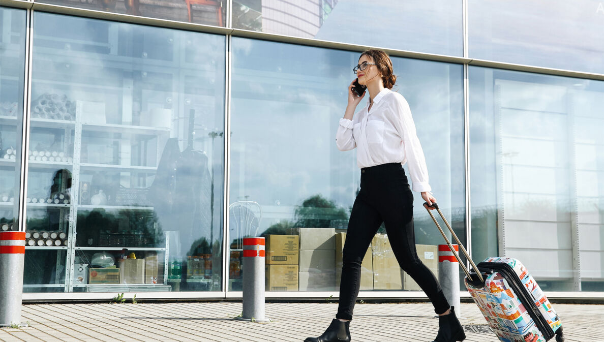 Eine Geschäftsfrau läuft mit ihrem Trolli zum Flughafen.