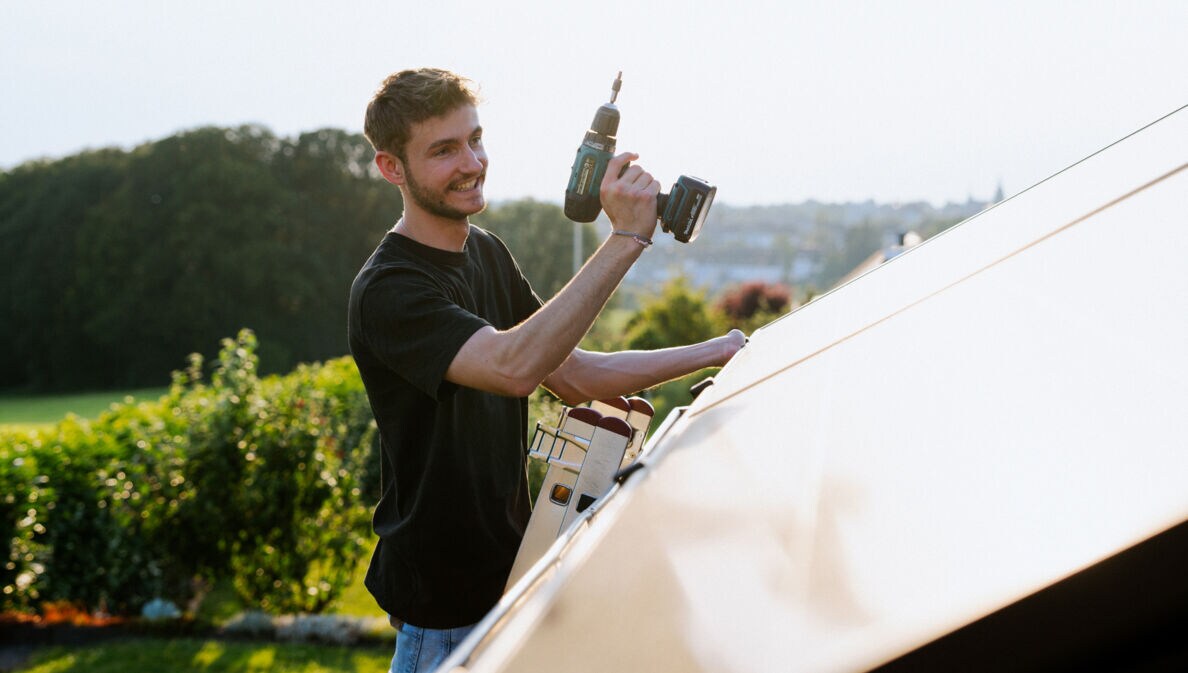 Janik Nolden, Co-Gründer der solago GmbH, arbeitet am Dach eines Hauses.