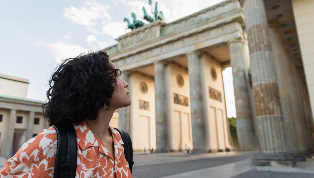 Eine junge Frau schaut auf das Brandenburger Tor.