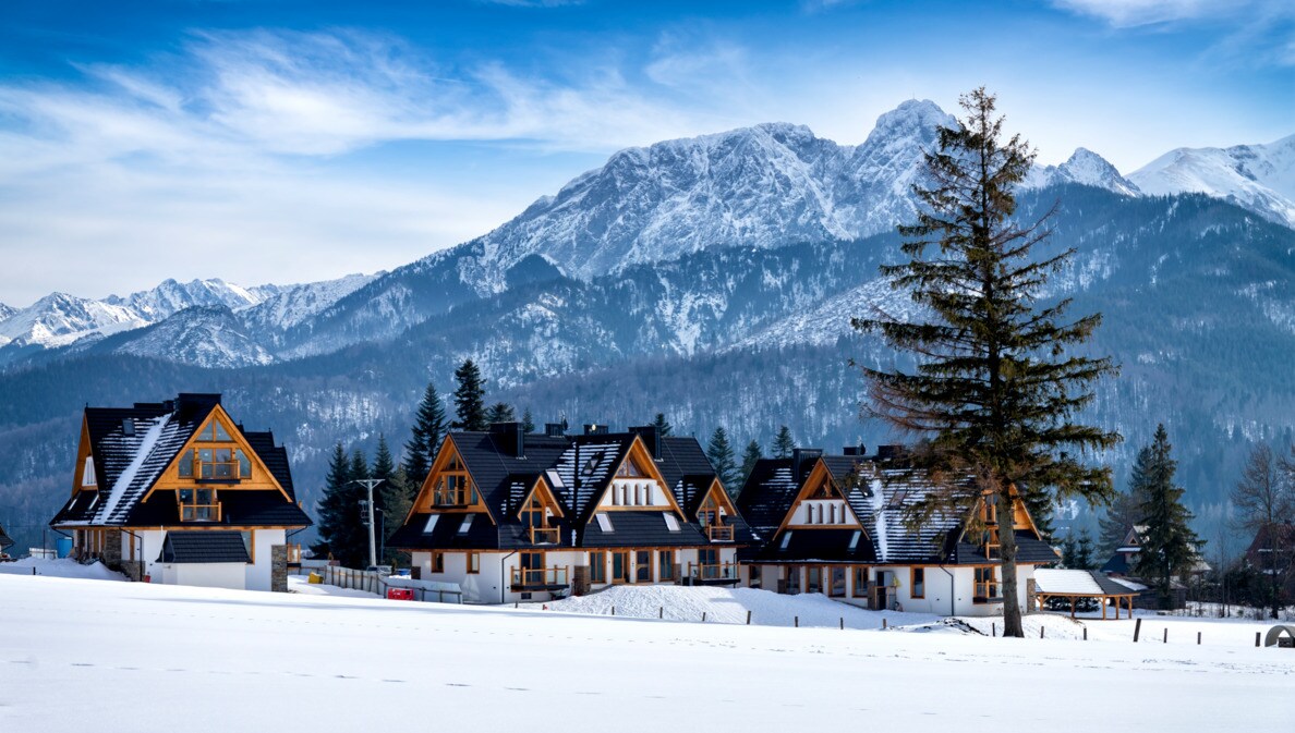 Das Dorf Kościelisko in der polnischen Tatra, im Hintergrund schneebedeckte Berge.