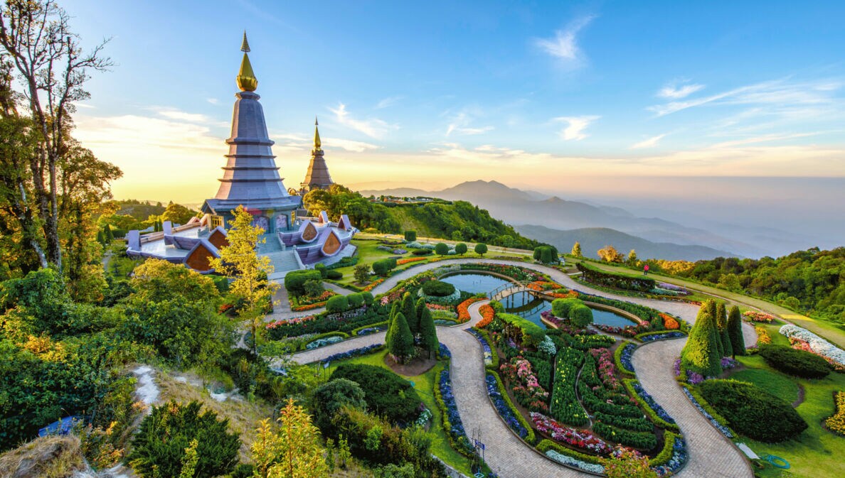 Buddhistische Tempelanlage mit spitzen Türmen und Landschaftsgarten auf einem Berg.