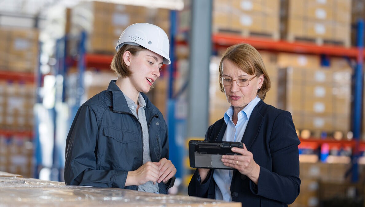 Zwei Frauen einer unterschiedlichen Generationen stehen zusammen in einem Lagerraum.