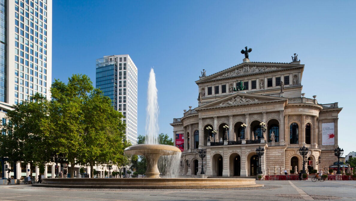 Opernplatz mit Springbrunnen und dahinterliegend das historische Gebäude der Alten Oper Frankfurt.