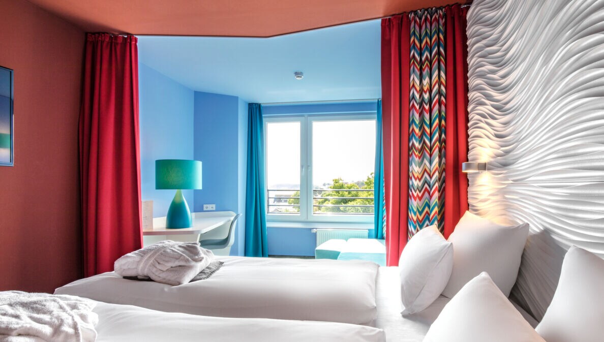 Modernes Hotelzimmer mit farbenfrohen Wänden und Strandblick.