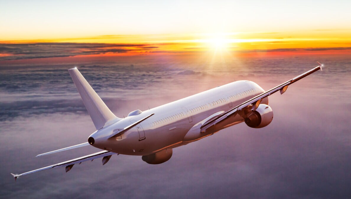 Ein geneigtes Passagierflugzeug über den Wolken bei Sonnenuntergang.