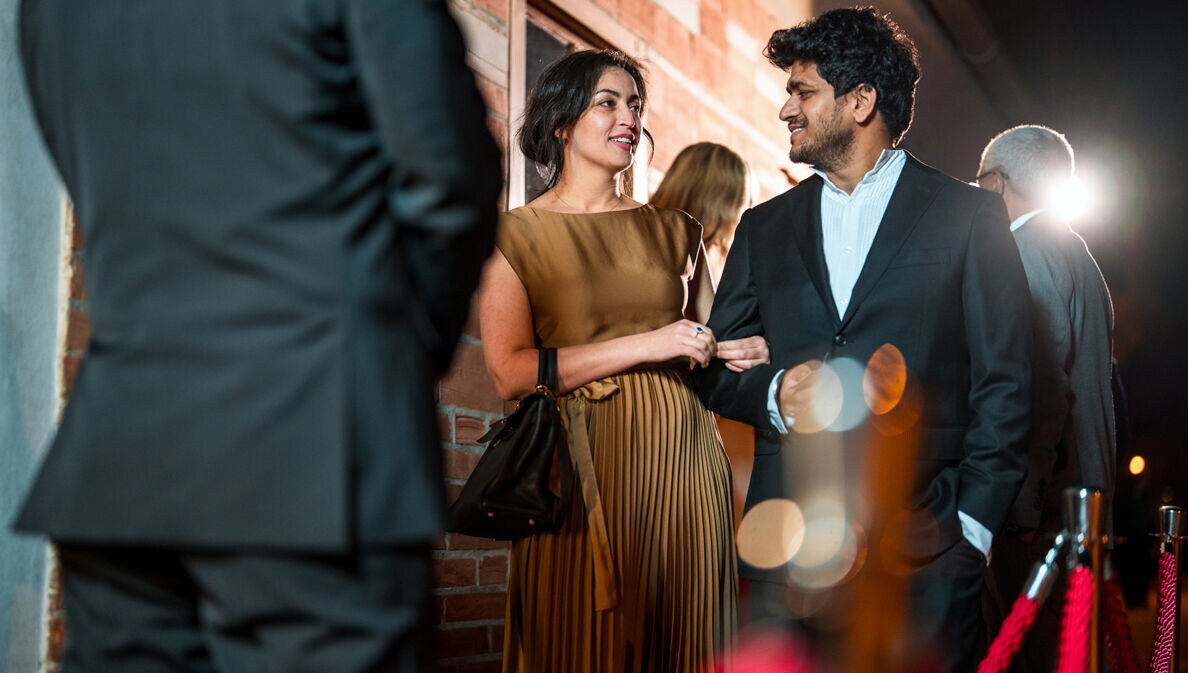 Ein glamouröses Paar steht vor dem Einlass eines exklusiven Events.