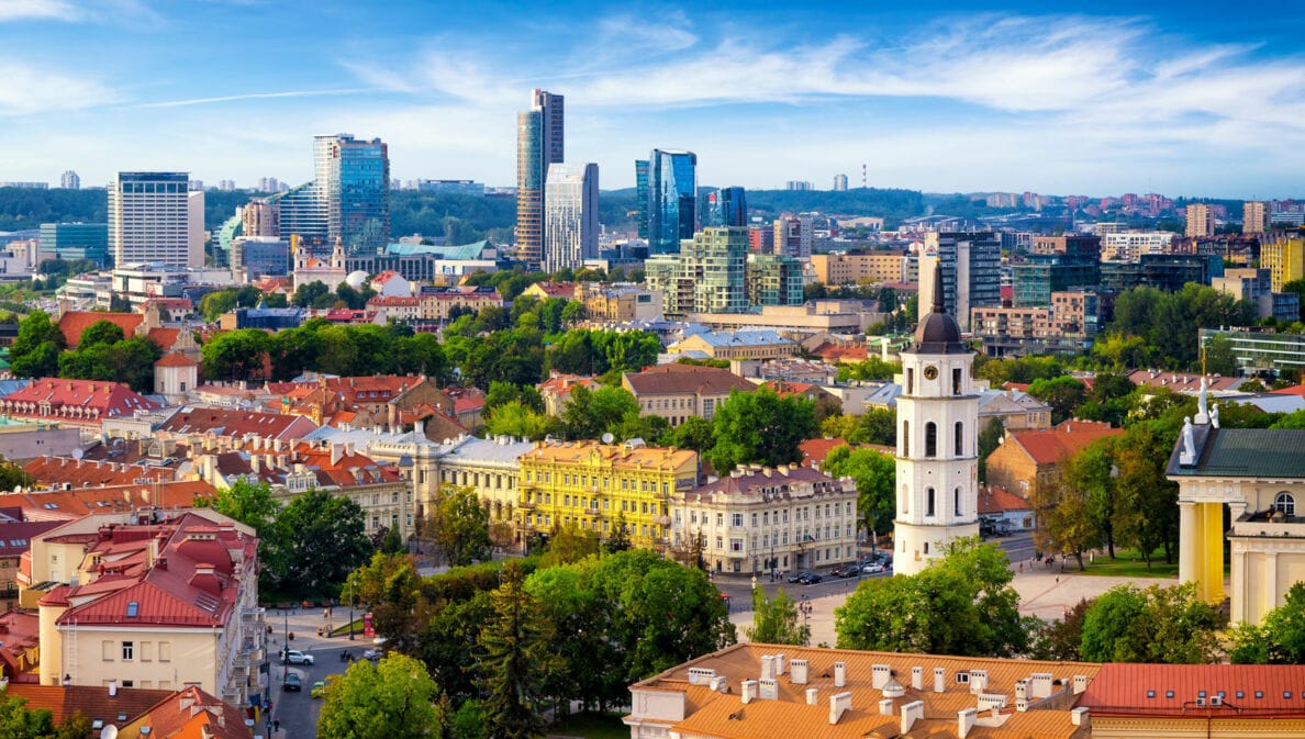 Stadtpanorama von Vilnius mit Kirchturm in Altstadt vor modernen Hochhäusern im Hintergrund.