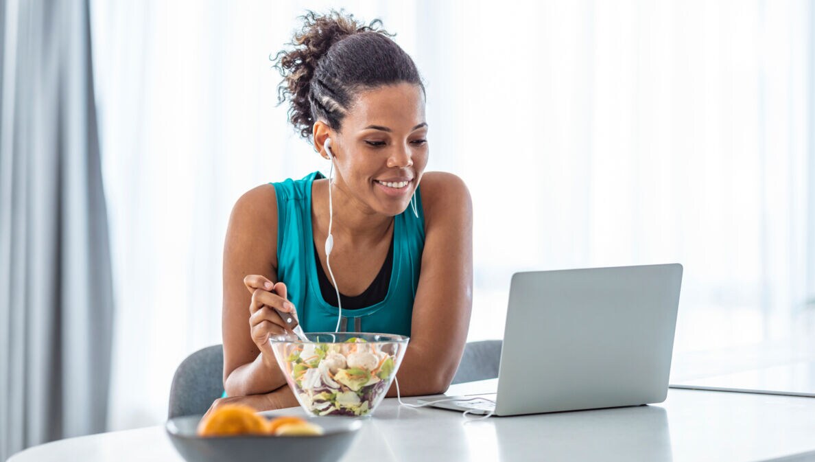 Eine Frau isst einen Salat an ihrem Arbeitsplatz.
