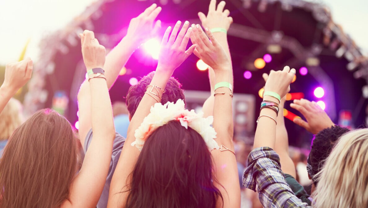 Jubelnde Personen von hinten vor eine Bühne.