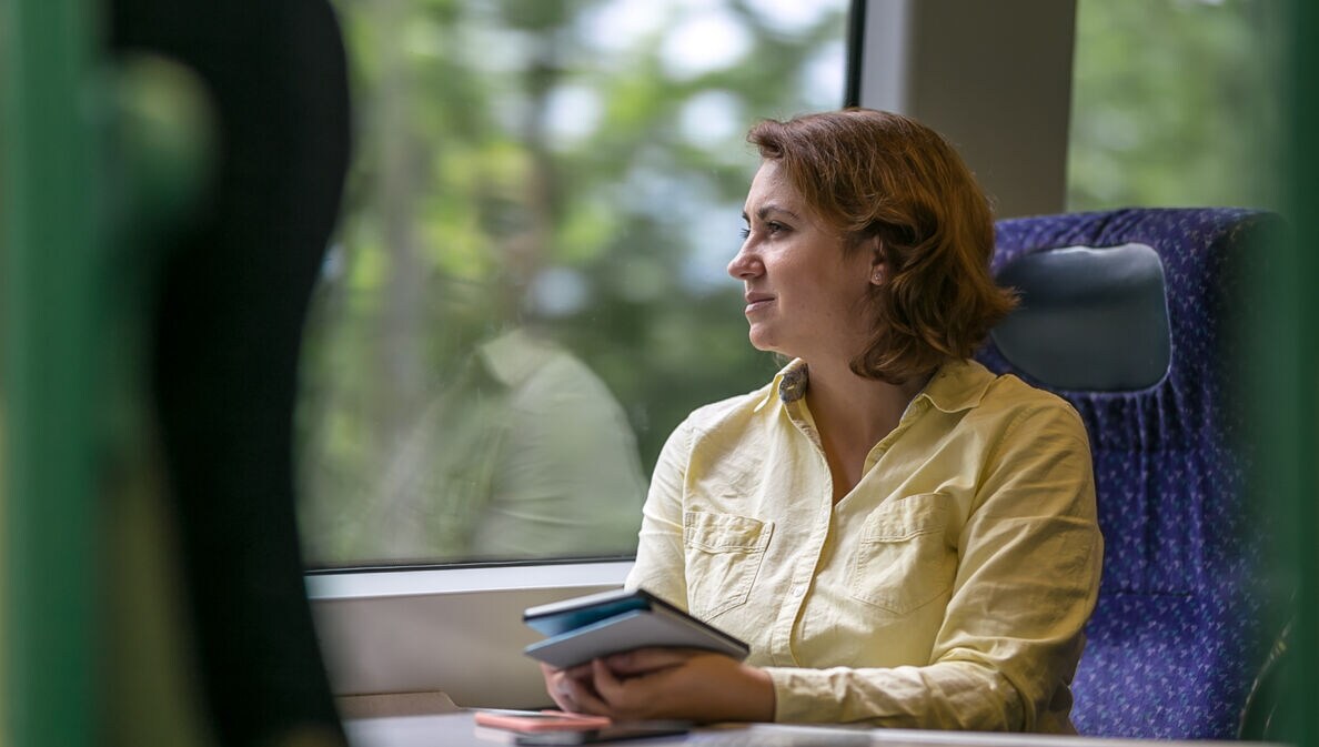 Eine Geschäftsfrau reist klimafreundlich im modernen Zug.