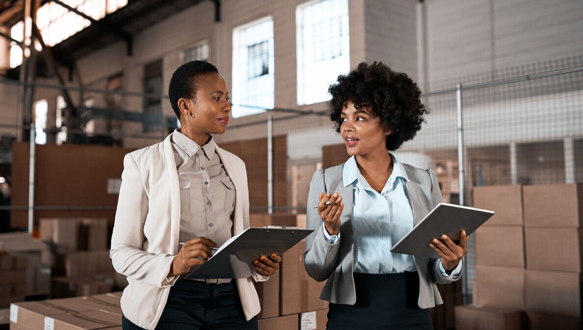 Zwei erfolgreiche weibliche Führungskräfte besprechen sich im Logistikzentrum.