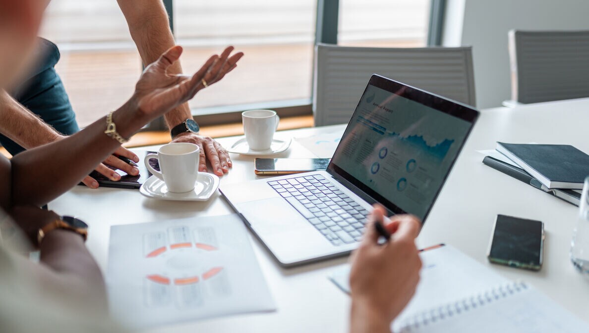 Das Bild zeigt eine Nahaufnahme eines Laptops während einer Besprechung des Buchhaltungsteams.