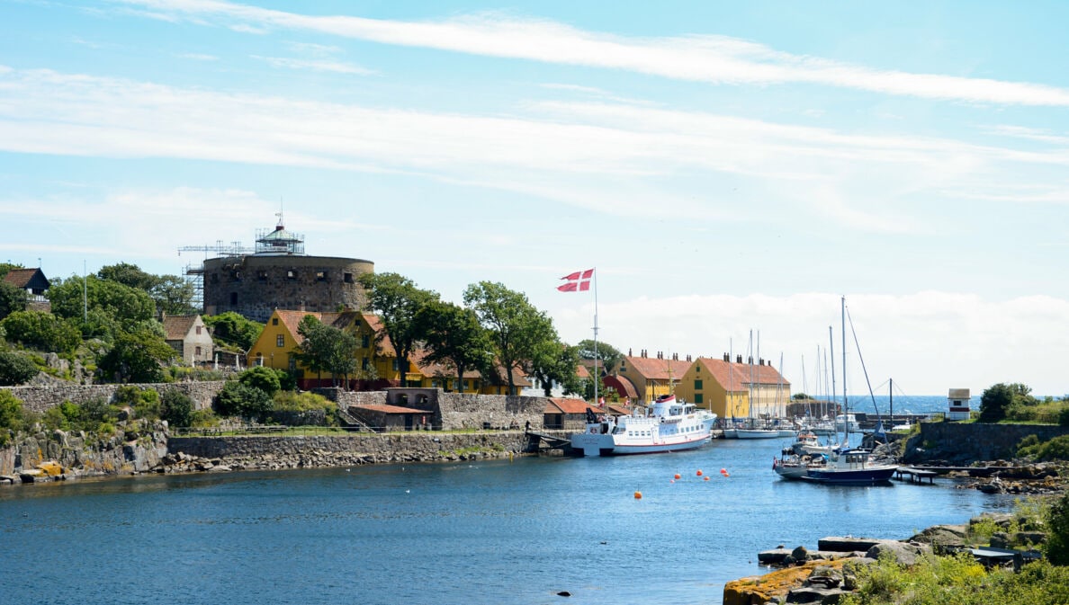 Hafen mit Segelbooten und Fähre, dänische Flagge weht, historische Festung und Häuser am Ufer auf Bornholm