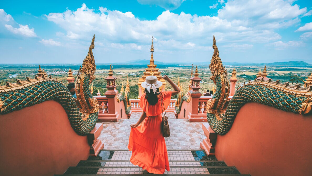 Eine Urlauberin steht in einer Tempelanlage in Thailand