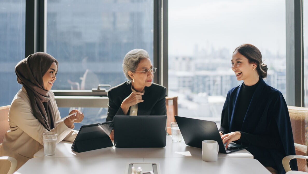 Teamgeist: Eine Gruppe von Frauen verschiedener Altersgruppen tauscht sich in einem hellen Meetingraum aus.
