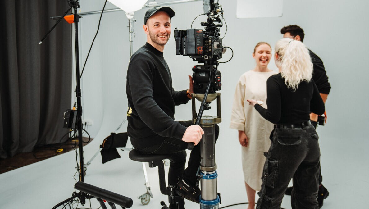 Fotografie von Dennis Schmelz an der Kamera im Filmstudio.