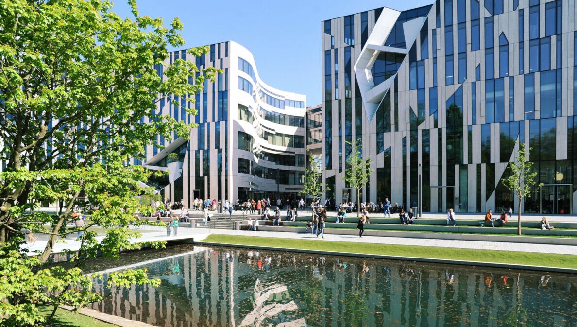 Moderne Bürogebäude mit Glasfassaden am Wasserbecken im Kö-Bogen Düsseldorf, Menschen sitzen und gehen auf der Promenade