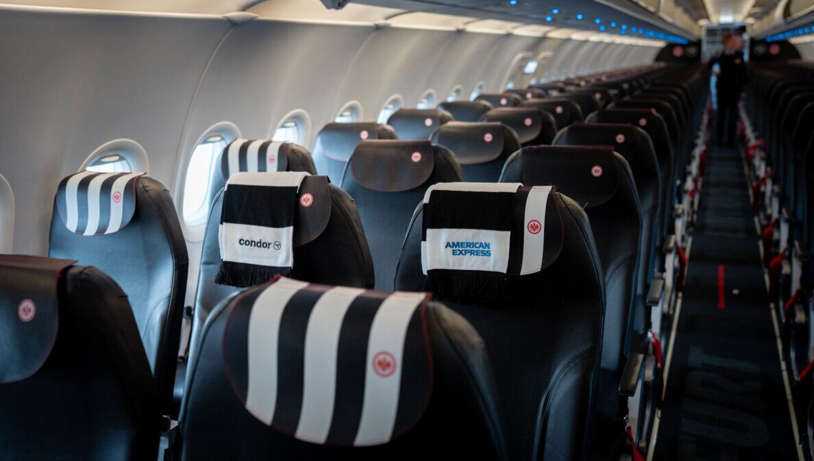 Sitzplätze eines Condor Business-Class-Fluges mit einem Fanschal der Eintracht Frankfurt über der Lehne.