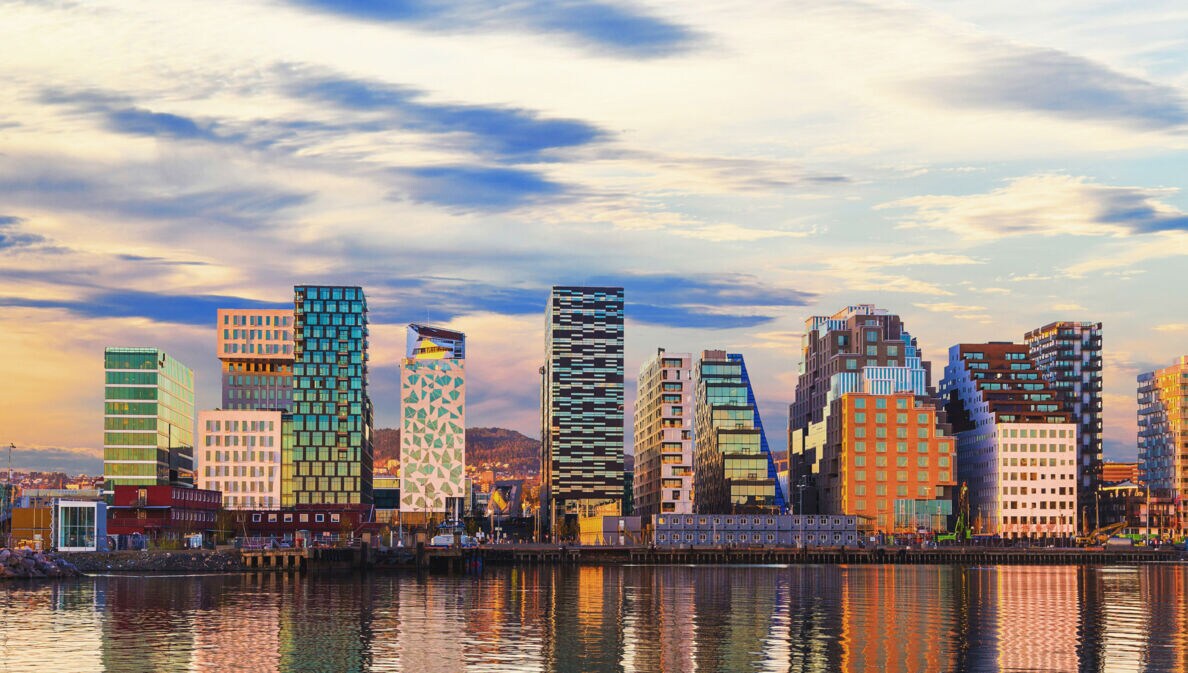 Eine Skyline mit verschieden Hochhäusern liegt direkt an einem Fluss.