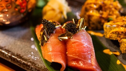 Nahaufnahme von edel angerichtetem Sashimi Sushi mit Blattgold und Kaviar.